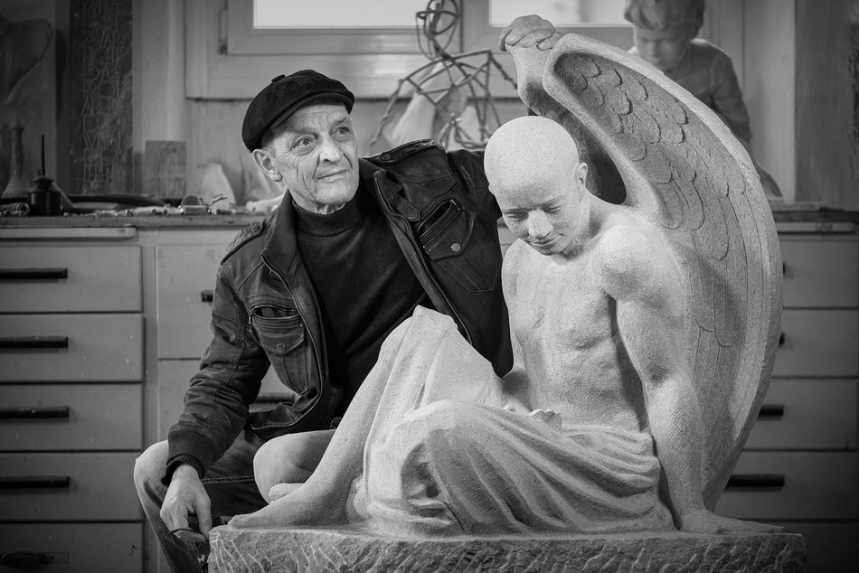 Bildhauer und Künstler Daniele Trebucchi neben seiner Engel Skulptur aus Kalkstein